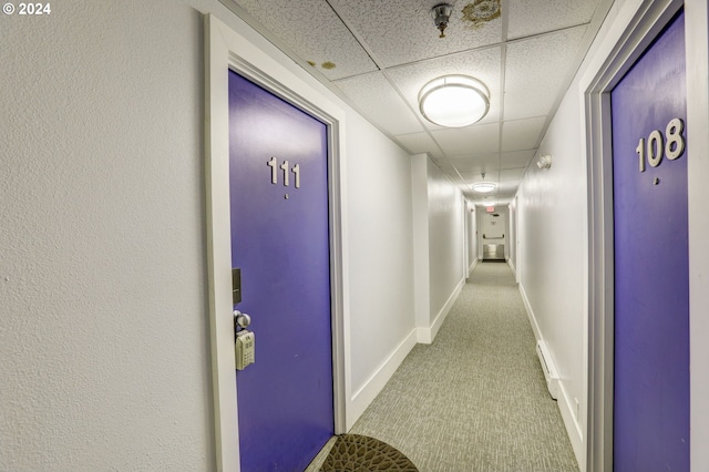 corridor with carpet, a drop ceiling, and baseboards