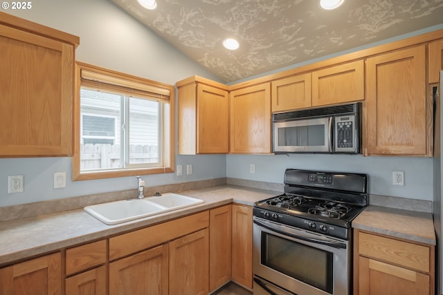 kitchen with lofted ceiling, appliances with stainless steel finishes, light countertops, and a sink