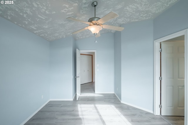 unfurnished room with baseboards, ceiling fan, a textured ceiling, and light wood-style floors