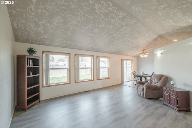 living area featuring light wood-type flooring and a textured ceiling