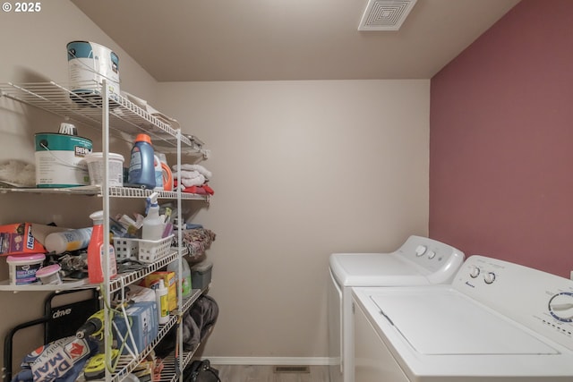 washroom featuring visible vents, washing machine and dryer, wood finished floors, laundry area, and baseboards