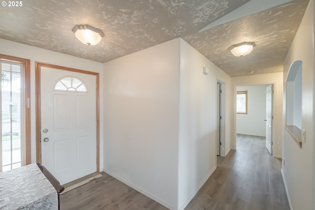 foyer with a textured ceiling, wood finished floors, and baseboards