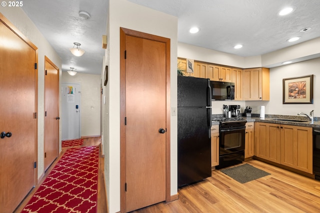 kitchen featuring sink, a textured ceiling, light wood-type flooring, and black appliances