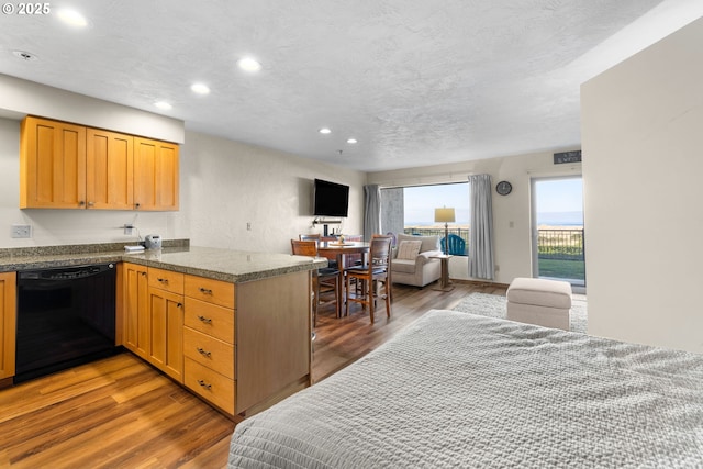 kitchen with a textured ceiling, wood-type flooring, kitchen peninsula, and dishwasher