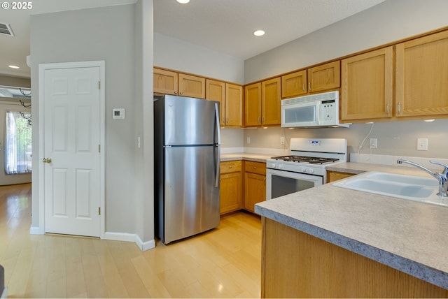 4338 NE 76th Ave, Portland, OR 97218 - kitchen with white appliances, light wood finished floors, light countertops, recessed lighting, and brown cabinets