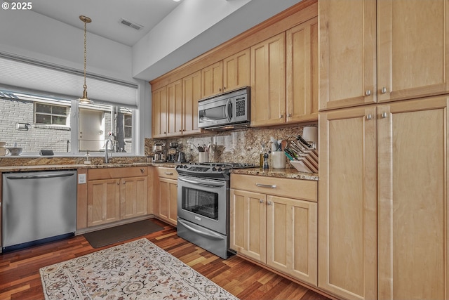 kitchen with dark wood-style floors, light brown cabinets, a sink, appliances with stainless steel finishes, and tasteful backsplash