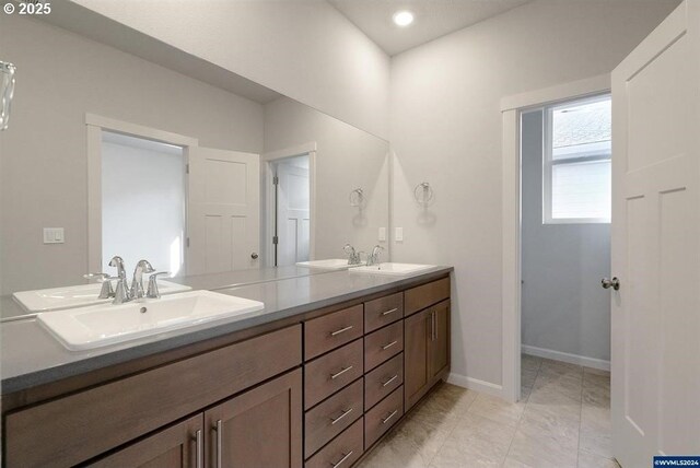 full bath featuring double vanity, baseboards, and a sink