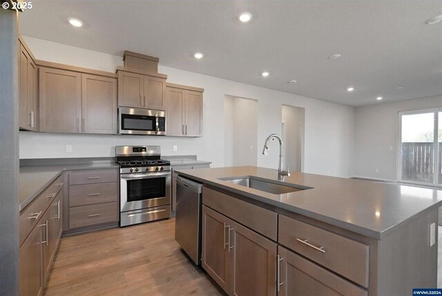 kitchen with stainless steel appliances, recessed lighting, a kitchen island with sink, and a sink