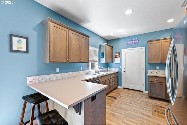 25092 Amber Ct, Veneta, OR 97487 - kitchen with freestanding refrigerator, a peninsula, a sink, a breakfast bar, and light wood finished floors