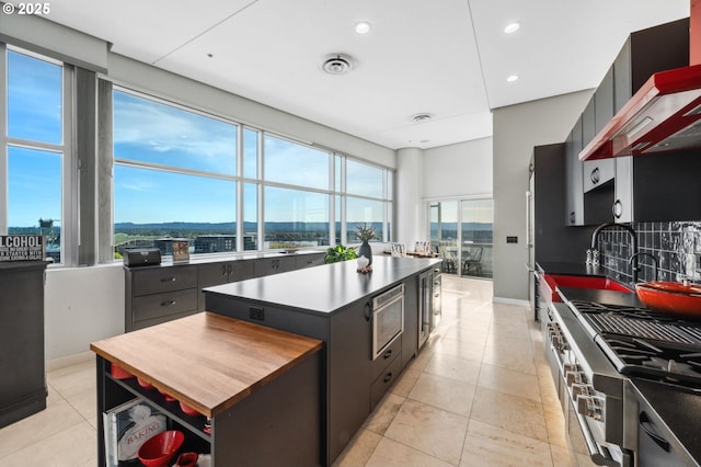 700 Washington St Unit 1125, Vancouver, WA 98660 - kitchen featuring wall chimney exhaust hood, dark countertops, a kitchen island, light tile patterned floors, and recessed lighting