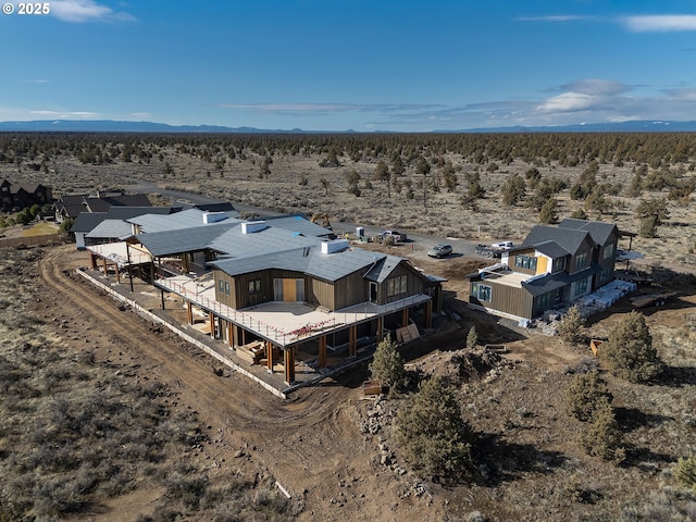 aerial view featuring a wooded view, a mountain view, and view of desert