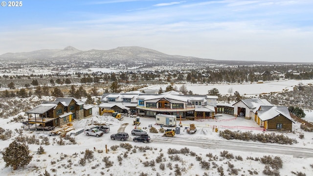 snowy aerial view featuring a mountain view and a residential view
