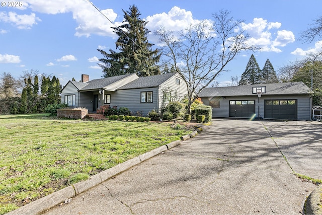 view of front of house with a chimney, a front yard, a garage, driveway, and an outdoor structure