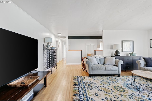 living area featuring light wood-style floors, visible vents, and baseboards