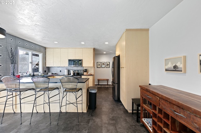 kitchen with finished concrete flooring, decorative backsplash, a breakfast bar area, stainless steel appliances, and recessed lighting