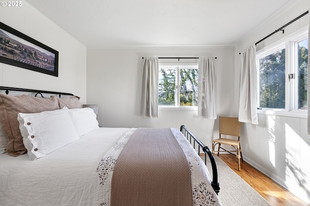 bedroom with crown molding, baseboards, and wood finished floors