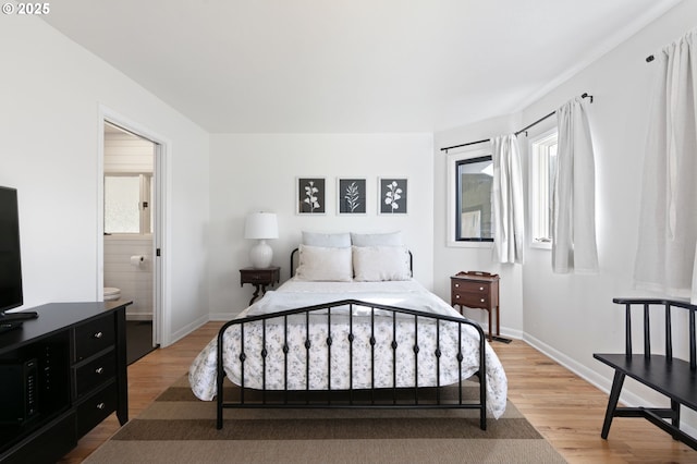 bedroom featuring light wood-style floors, ensuite bath, and baseboards