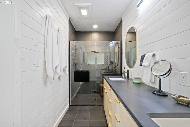 full bath with double vanity, a stall shower, tile patterned flooring, and a sink