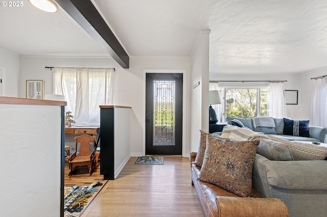 foyer entrance with wood finished floors, beam ceiling, and baseboards