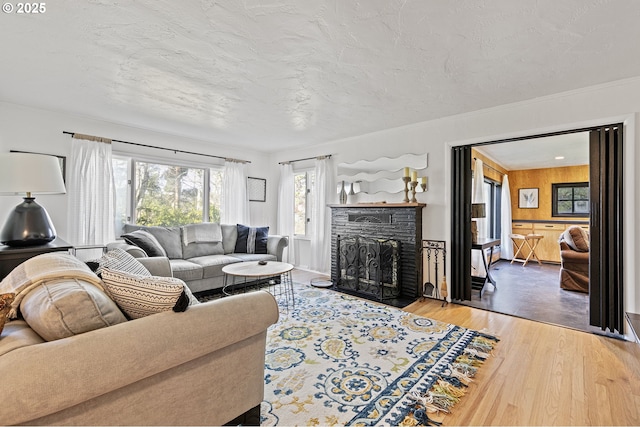 living area with crown molding, a fireplace, a textured ceiling, and wood finished floors