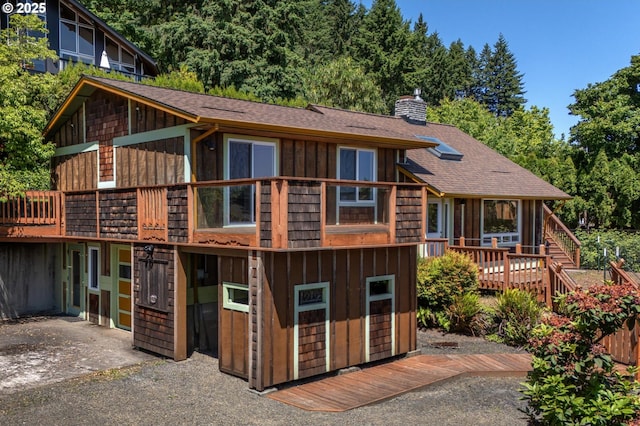 32813 NW Peak Rd, Scappoose, OR 97056 - view of front of home with a chimney, a shingled roof, a deck, board and batten siding, and stairway