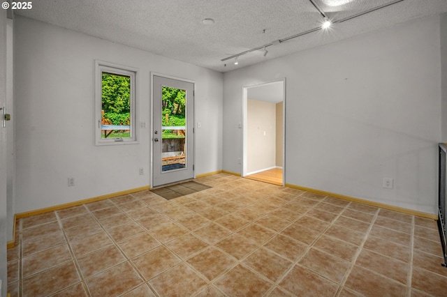 32813 NW Peak Rd, Scappoose, OR 97056 - tiled empty room featuring track lighting, a textured ceiling, and baseboards