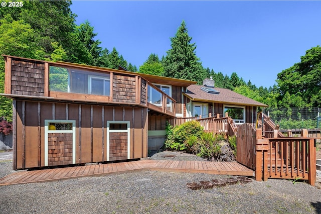 32813 NW Peak Rd, Scappoose, OR 97056 - view of front of house with a wooden deck, board and batten siding, an attached garage, gravel driveway, and stairway