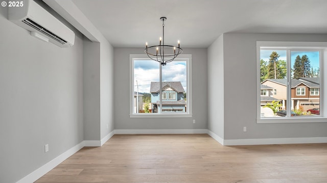 unfurnished dining area featuring a wall mounted air conditioner, light hardwood / wood-style flooring, and a notable chandelier