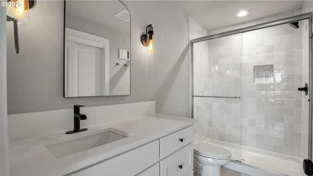 bathroom with walk in shower, vanity, and toilet