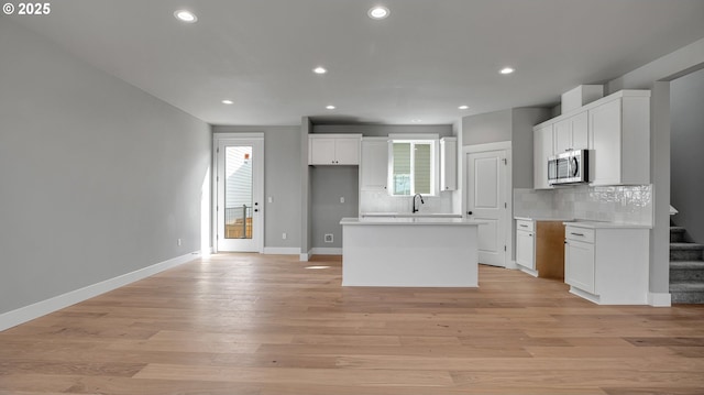 kitchen with white cabinetry, a kitchen island, and light hardwood / wood-style flooring