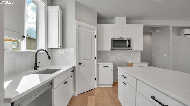 kitchen with dishwasher, backsplash, white cabinetry, and sink