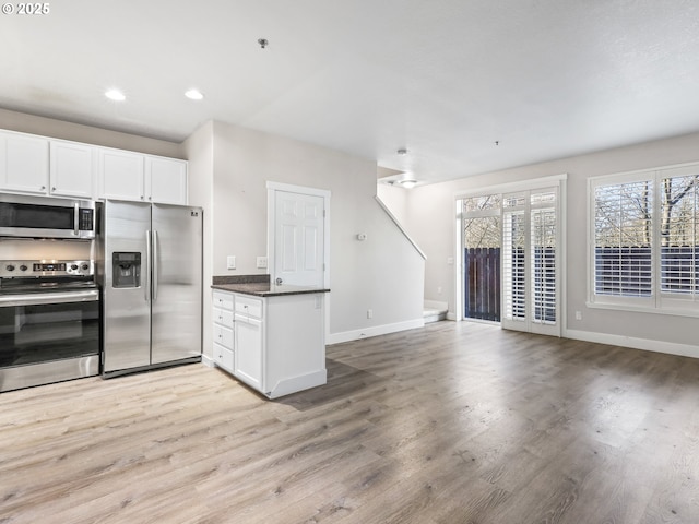 kitchen with appliances with stainless steel finishes, white cabinets, and light wood-type flooring