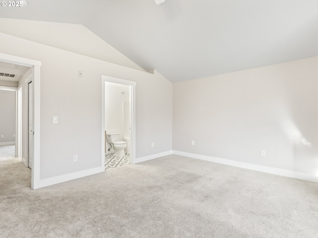 unfurnished bedroom featuring vaulted ceiling, light carpet, and connected bathroom