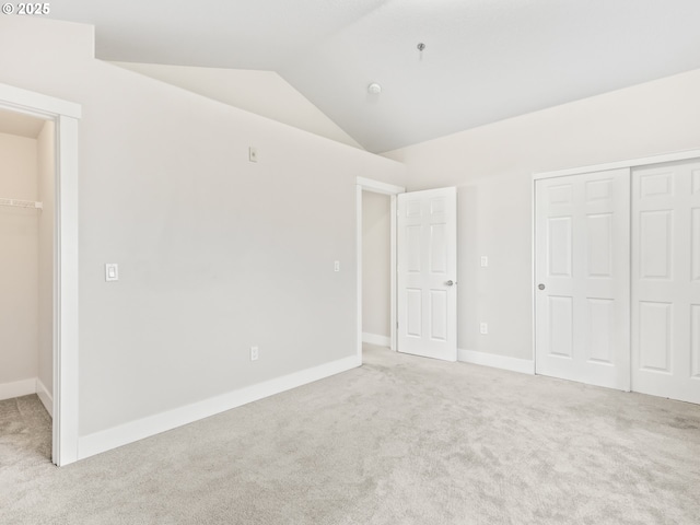 unfurnished bedroom with lofted ceiling, light carpet, and a closet