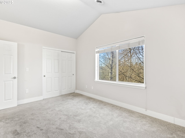 unfurnished bedroom with carpet floors, vaulted ceiling, and a closet