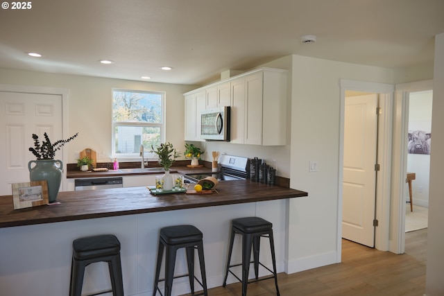 46412 Lyons Mill City Dr, Lyons, OR 97358 - kitchen featuring stainless steel appliances, a sink, white cabinetry, wood finished floors, and wood counters