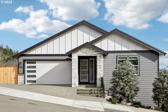 view of front of property featuring driveway, stone siding, an attached garage, fence, and board and batten siding