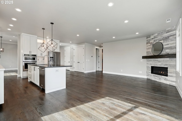1730 N 12th St, Washougal, WA 98671 - kitchen with appliances with stainless steel finishes, dark countertops, open floor plan, a tiled fireplace, and a center island with sink