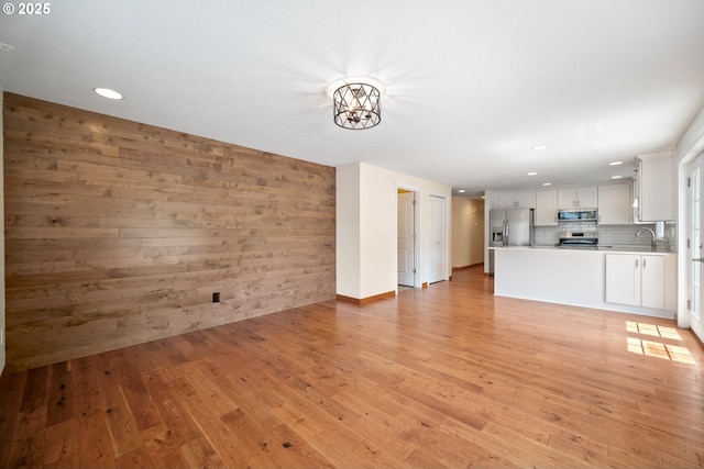 1602 NE 16th Ct, Battle Ground, WA 98604 - unfurnished living room featuring a sink, recessed lighting, light wood-type flooring, a chandelier, and wooden walls
