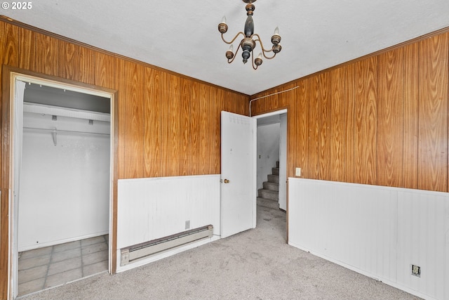 180 W Second Ave, Sutherlin, OR 97479 - unfurnished bedroom with a baseboard radiator, a chandelier, wooden walls, a closet, and carpet flooring
