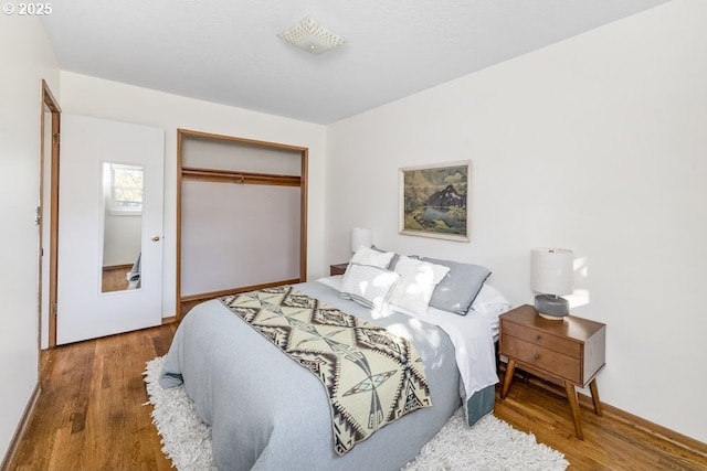 bedroom with a closet, baseboards, and wood finished floors