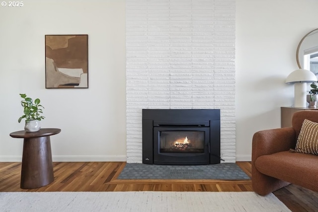 interior details with baseboards, a large fireplace, and wood finished floors