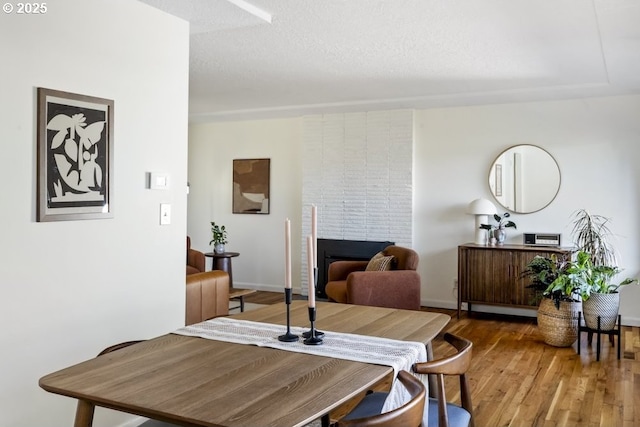 dining room with a fireplace, wood finished floors, and a textured ceiling