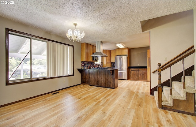 8400 Cason Rd, Gladstone, OR 97027 - kitchen with freestanding refrigerator, island exhaust hood, dark countertops, a peninsula, and a chandelier