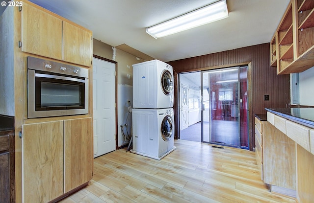 8400 Cason Rd, Gladstone, OR 97027 - kitchen featuring stacked washer / dryer, stainless steel oven, light brown cabinets, light wood finished floors, and open shelves