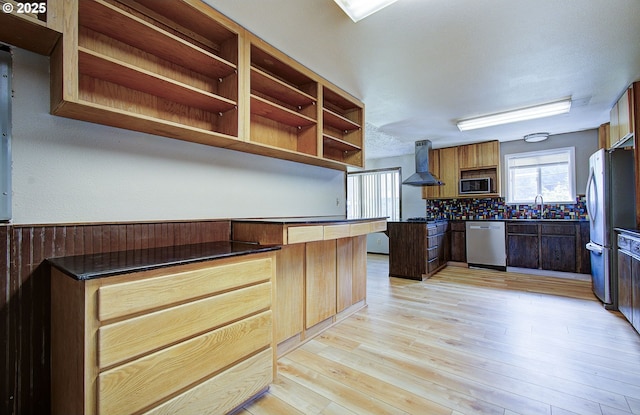 8400 Cason Rd, Gladstone, OR 97027 - kitchen featuring stainless steel appliances, wall chimney exhaust hood, dark countertops, backsplash, and light wood-style flooring