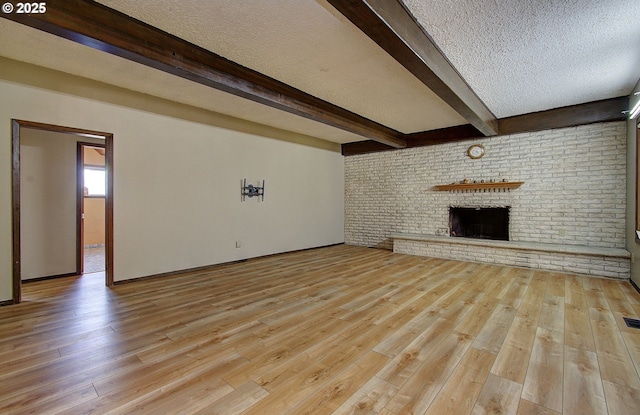 8400 Cason Rd, Gladstone, OR 97027 - unfurnished living room with wood finished floors, beam ceiling, a brick fireplace, and a textured ceiling