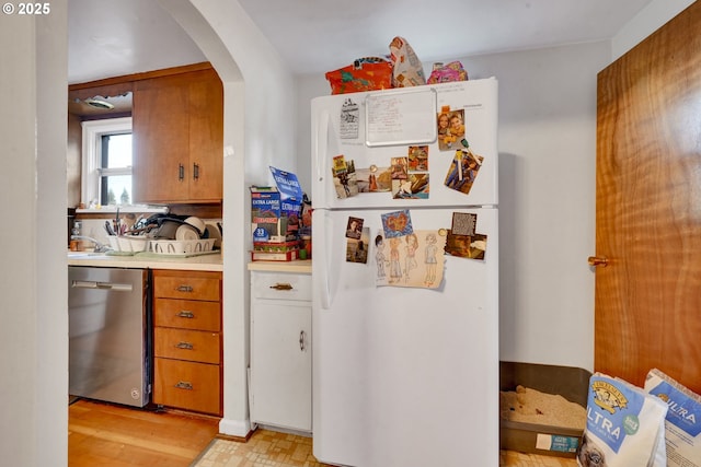 1648 Augusta St, Eugene, OR 97403 - kitchen with freestanding refrigerator, stainless steel dishwasher, arched walkways, light countertops, and brown cabinetry