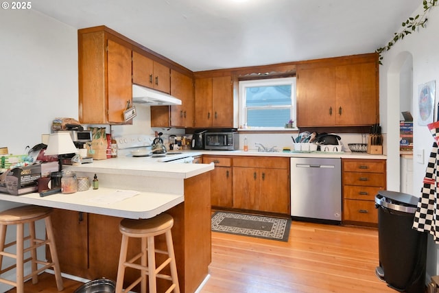 1648 Augusta St, Eugene, OR 97403 - kitchen featuring stainless steel dishwasher, under cabinet range hood, white stove, brown cabinets, and light countertops