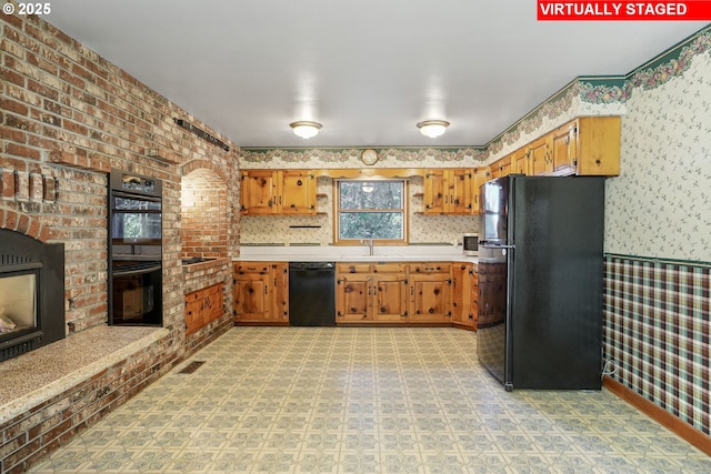 kitchen featuring light floors, wallpapered walls, a fireplace, black appliances, and light countertops